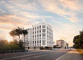 Un hotel moderno con fachada curva, varios balcones y una entrada destacada.