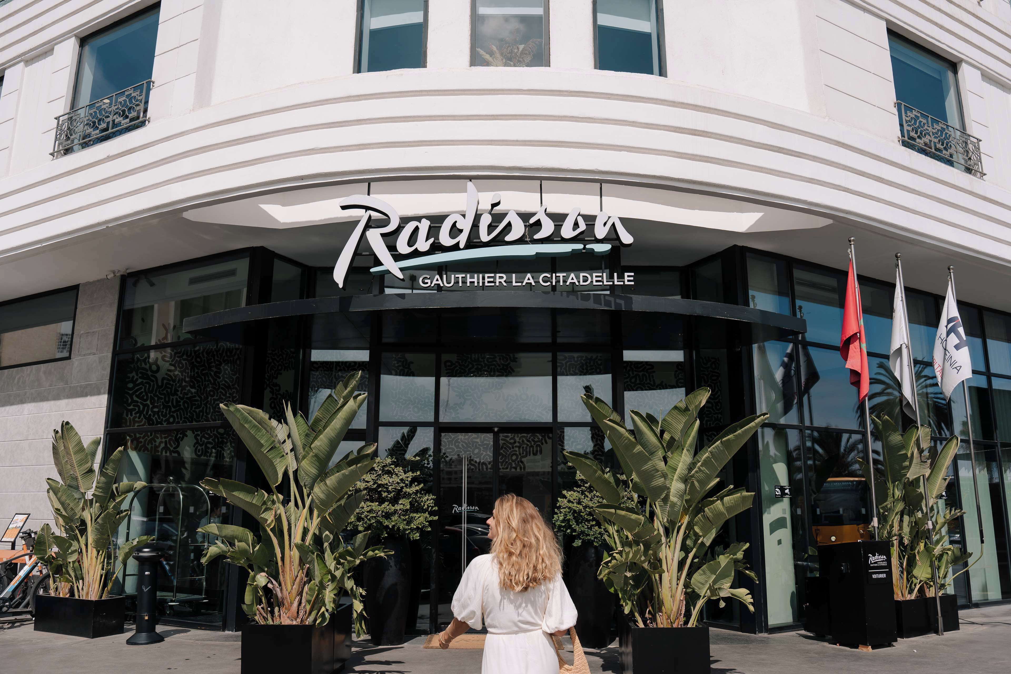 The Radisson hotel entrance with a curved facade, large glass windows, and potted plants in front.