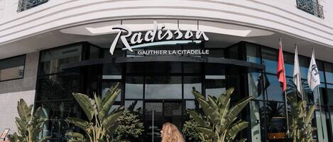 The Radisson hotel entrance with a curved facade, large glass windows, and potted plants in front.