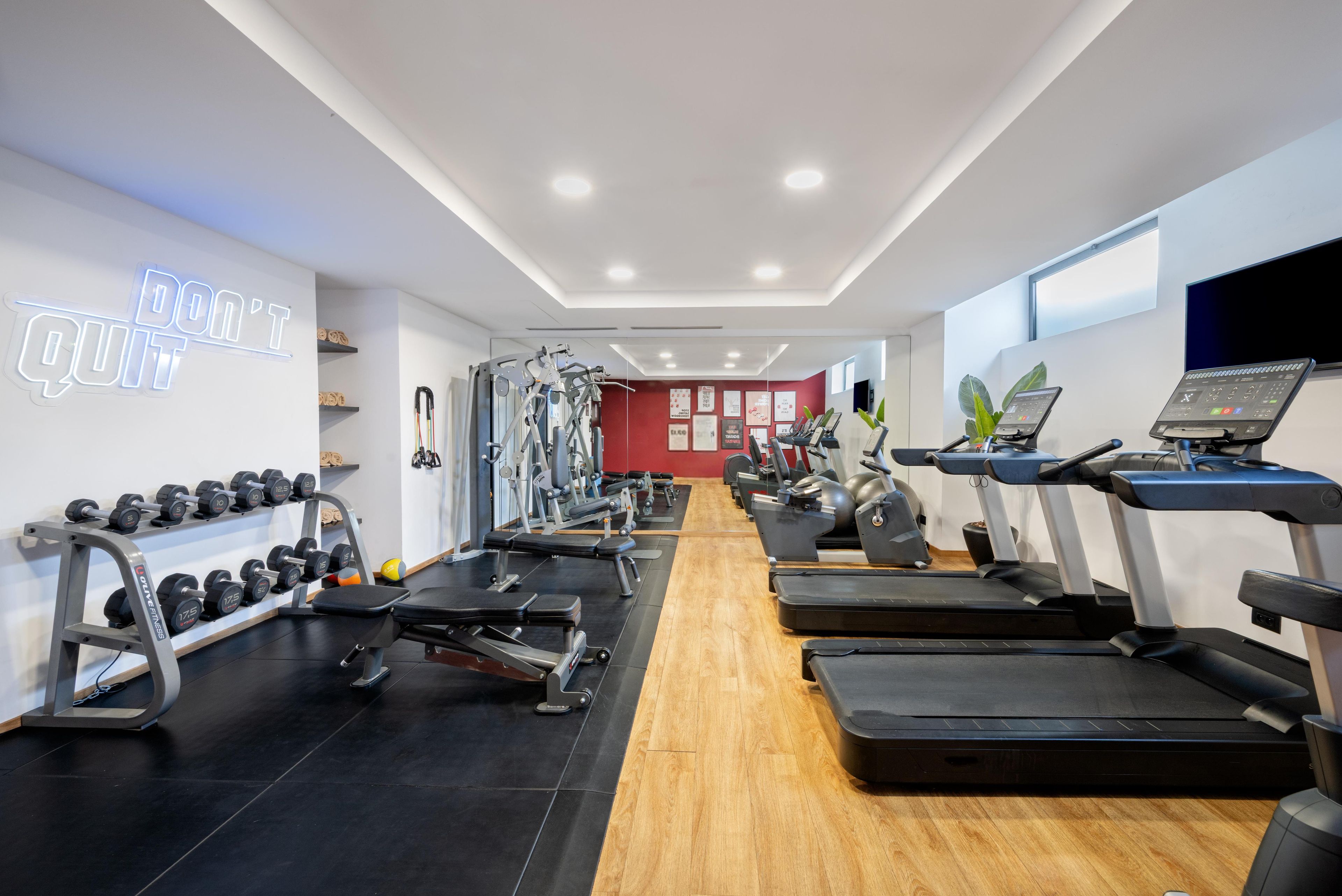 A gym with treadmills, weight machines, and dumbbells.