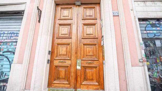 A wooden double door with a brass handle and a small plaque above it. - Binaro 0 a Termini (Rome)