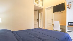 A hotel room with a bed, a desk, a chair, a TV, and a door. - Binaro 0 a Termini (Rome)