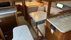 Un intérieur de camping-car compact comprenant un coin cuisine, un espace repas et un espace nuit.