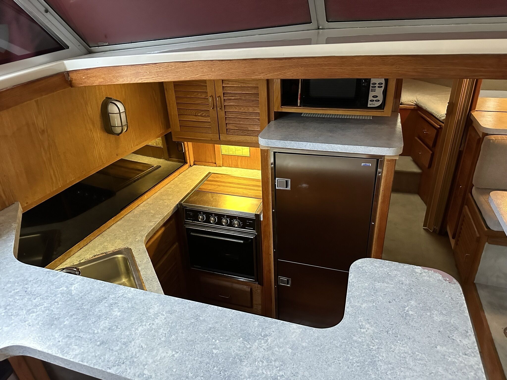A compact kitchenette with a stove, sink, microwave, and storage cabinet.