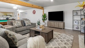 A modern living room with a sofa, coffee table, and TV. - A&M SPORTS DAY, POOL TABLE, AND BBQ (College Station)