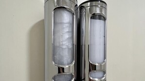 Two cylindrical objects with reflective surfaces and transparent sections, mounted on a wall.