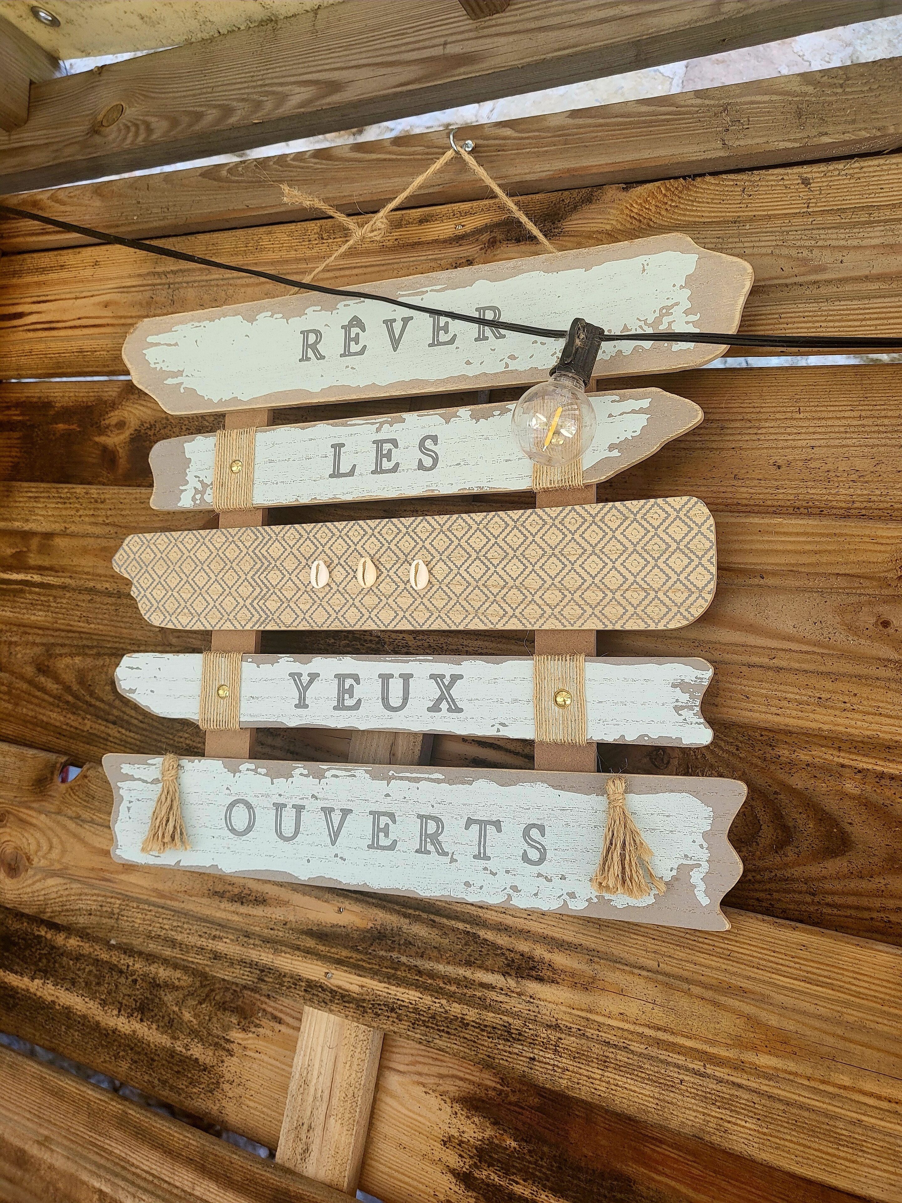 Un mur en bois rustique orné de panneaux décoratifs sur lesquels on peut lire : « RÊVEZ LES YEUX OUVERTS ».