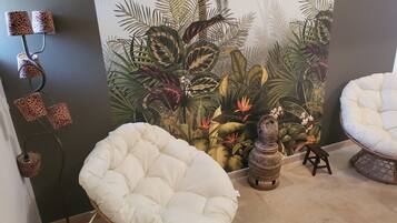 A room with a white cushioned chair, a small table, and a decorative wall mural.