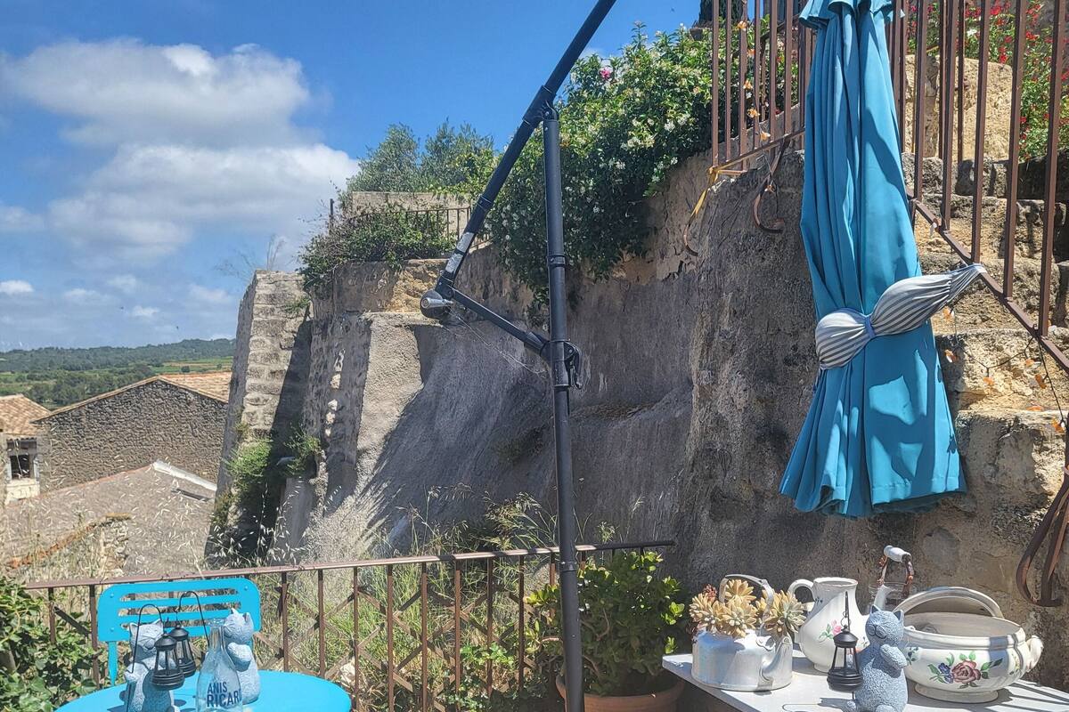 Un patio con una mesa y sillas azules, una planta en maceta y mobiliario exterior.