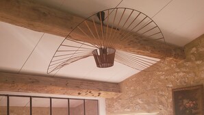 Una habitación con sofá, una mesita, una silla, un ventanal grande y una lámpara de techo original.