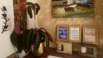 Una habitación con un cuadro grande de barcos, una planta en maceta y varios carteles enmarcados en la pared.