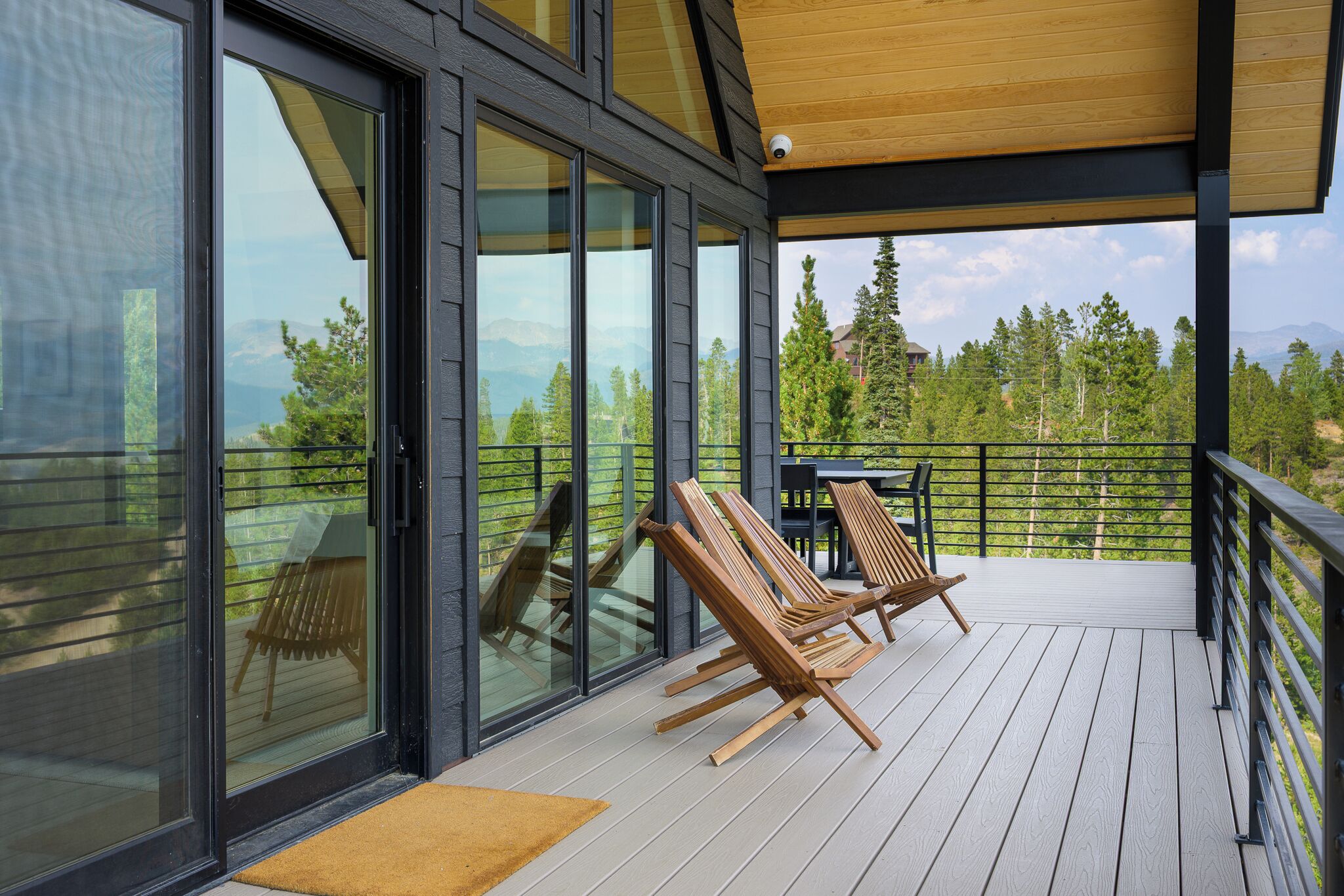 Une terrasse dotée de portes-fenêtres coulissantes, de chaises en bois et d’une table.