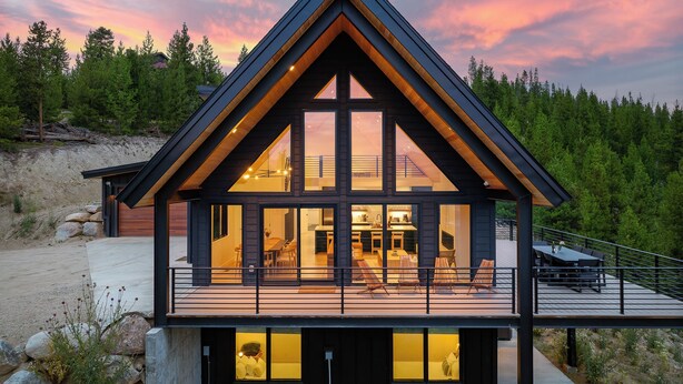 A modern cabin with a large deck, large windows, and a view of the surrounding forest. - Modern Mountain Escape | Hot Tub & Fireplace (Tabernash)