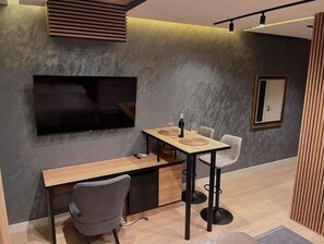 Cozy living space with a desk, flat-screen TV, and seating area.