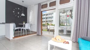 Una sala de estar moderna con comedor, un ventanal y vista a un balcón.
