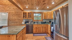 Une cuisine avec des meubles en bois, un réfrigérateur en acier inoxydable et un plan de travail en granit.