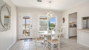Una cocina con mesa de comedor, sillas, una lámpara de araña y vistas a través de una puerta.
