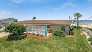 Une maison de plain-pied avec un patio couvert, une petite pelouse et une vue sur l’océan.
