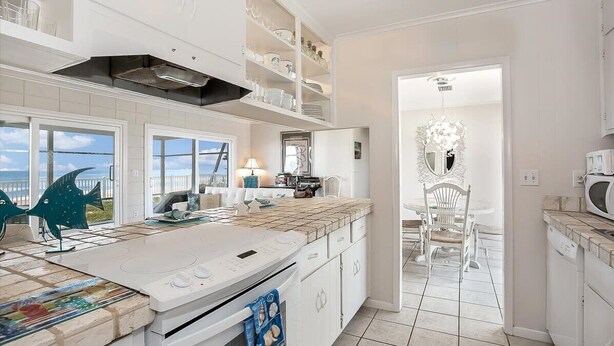 Une cuisine moderne avec des meubles blancs, un grand îlot central et une vue sur la mer.