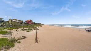 Una playa con un paseo de madera que lleva a un edificio de techo rojo.