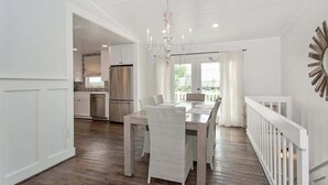 A spacious dining area with a wooden table and chairs, a chandelier, and a view of the outdoors. - Sandy Chic Home with Oceanfront Deck & Fireplace (Ponte Vedra Beach)