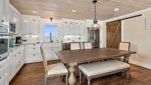 Una cocina moderna con armarios blancos, una mesa de comedor de madera y un amplio ventanal.