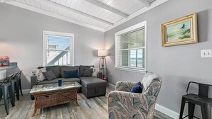 A living room with a sectional sofa, a patterned armchair, a glass coffee table, and a lamp.