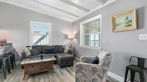 A living room with a sectional sofa, a patterned armchair, a glass coffee table, and a lamp.