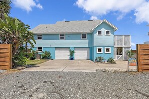 A two-story house with a garage, a wooden fence, and a small garden. - Seaside Sanctuary Home, Studio & Beach Walkout (St. Augustine)