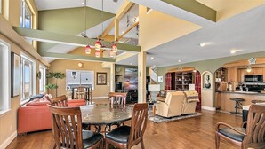 A spacious living area with a dining table, chairs, and a sofa. There is a kitchen area with cabinets and a microwave.