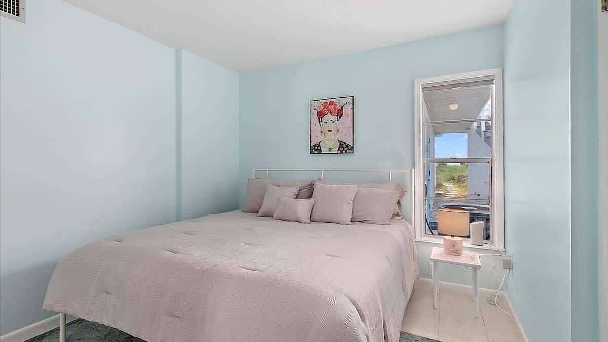 A bedroom with a bed, a window, a bedside table, and a wall-mounted artwork.