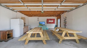 A rustic kitchen with wooden tables, a refrigerator, and a television.