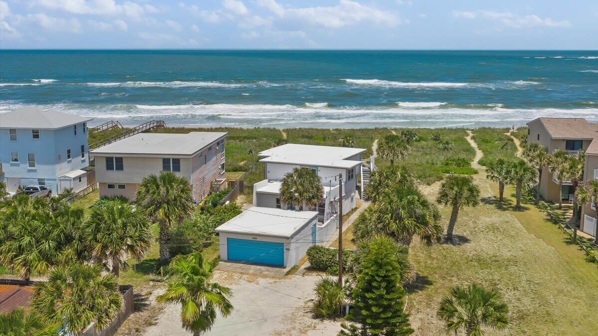 Un área residencial costera con casas, una playa y una vista despejada del océano.