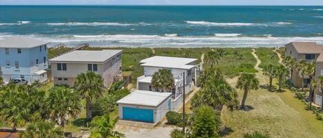 A coastal residential area with houses, a beach, and a clear view of the ocean.