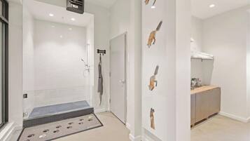 A modern bathroom with a glass shower enclosure, a dog-themed wall decoration, and a small wooden vanity.