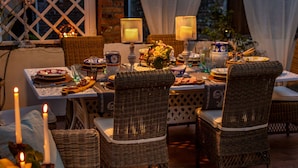 An outdoor dining area with wicker furniture, candles, and a table set for a meal. - Casa Celeste With Terrace (Lucca)