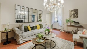 A living room with a sofa, coffee table, and chandelier. - Casa Celeste With Terrace (Lucca)