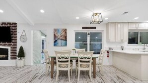 A modern kitchen with white cabinets, a dining area with a wooden table and chairs, and a brick fireplace. - 5 Bedroom 3 Bath in Northwest SA (San Antonio)