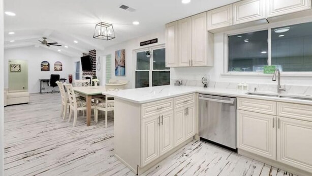 A modern kitchen with white cabinetry, a large island, and a dining area with chairs. - 5 Bedroom 3 Bath in Northwest SA (San Antonio)