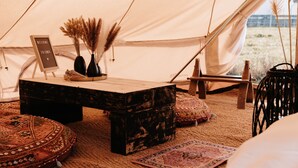 Een tent met een houten tafel, een welkomstbord en decoratieve objecten.