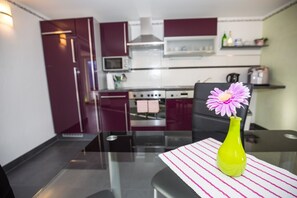 Enjoy meals at the glass-top dining table in this kitchen, equipped with a stove, microwave, and range hood.