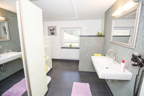 Features a sleek vanity, separate sink, and handheld showerhead.
