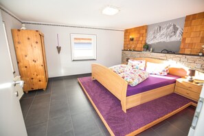 Relax in a serene bedroom with a large bed, a wooden wardrobe, and a window offering a scenic view.
