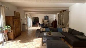 A spacious living room with a sofa, ottoman, and a dining area in the background.
