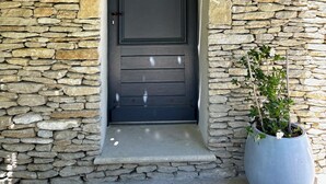A stone wall entrance with a dark door, a sign reading "COIFFEUR", and a potted plant beside it.