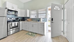 Una cocina moderna con electrodomésticos de acero inoxidable, armarios blancos y suelo de madera.
