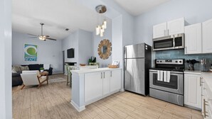 Una cocina moderna con armarios blancos, electrodomésticos de acero inoxidable y una isla central.