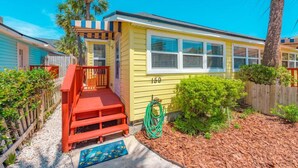 A yellow house with a red front porch and a number '159' on the side.