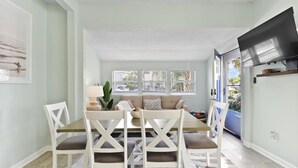 A dining area with a table and chairs, a sofa, and a television.