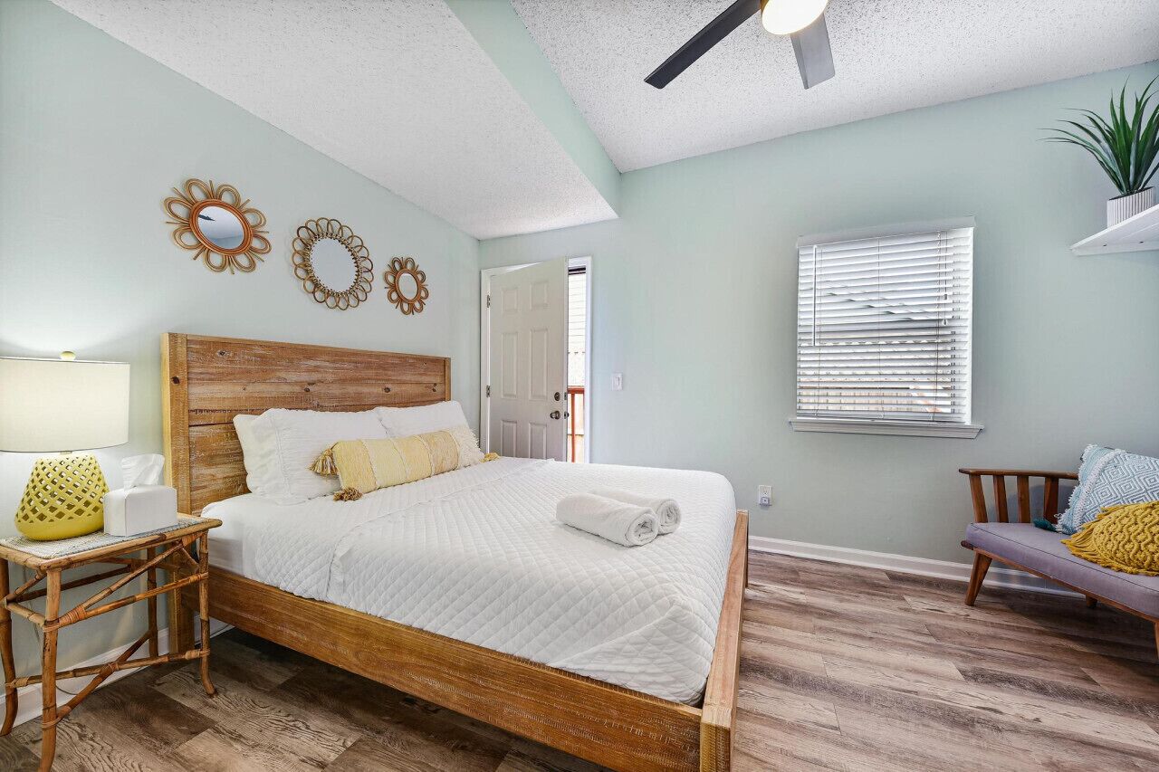 A bedroom with a wooden bed, a nightstand, a lamp, and decorative wall mirrors.